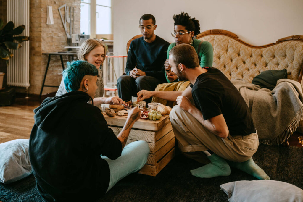 A group of five people sitting in a cozy living room around a wooden coffee table