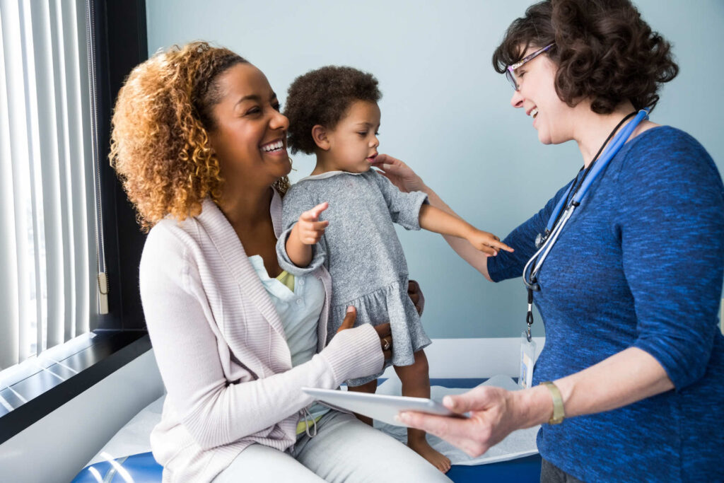 A mother holding her child while talking to a doctor in a medical office